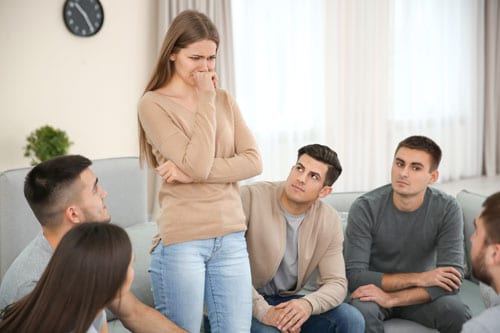 young adults surround an upset woman in a therapy setting